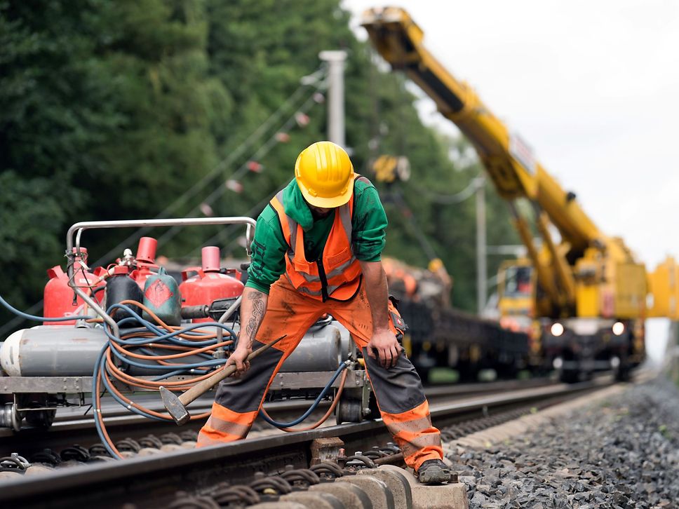 Shows a construction worker dismantling and loading a slab track